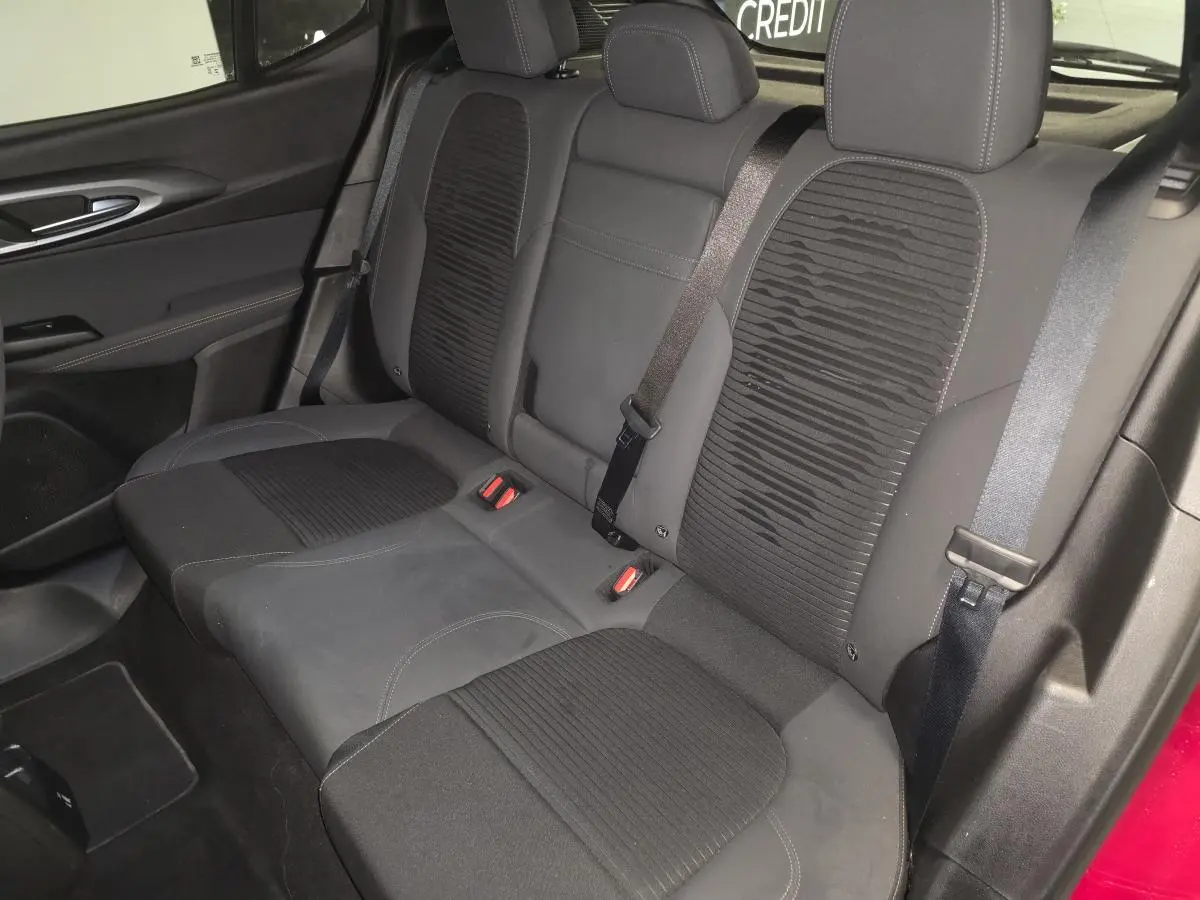 Vue intérieure de la banquette arrière noire de l'Alfa Romeo Tonale 2025, avec ceinture de sécurité et porte rouge partiellement visible.