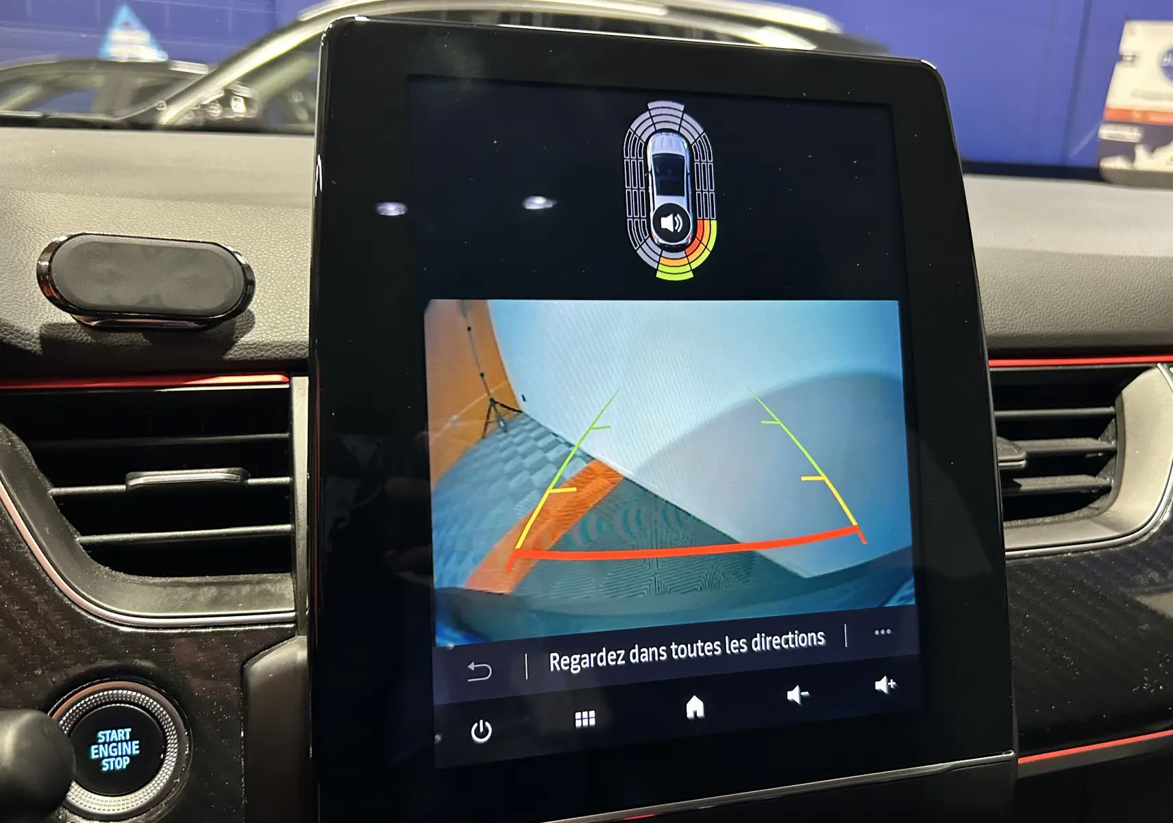 Écran central tactile montrant la caméra de recul avec alertes de proximité sur Renault Arkana noir, vue intérieure avant.