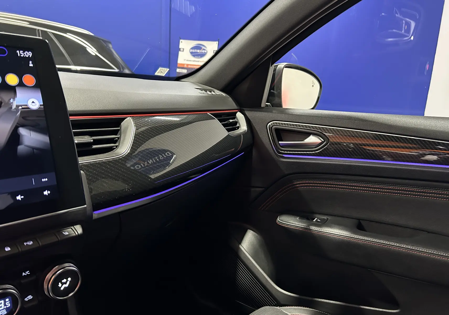 Vue intérieure côté passager du tableau de bord noir avec insert carbone et éclairage d’ambiance violet sur Renault Arkana E-Tech 2022.