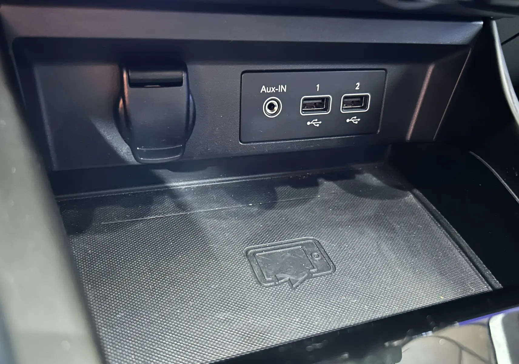 Gros plan sur la console centrale noire du Renault Arkana, montrant les ports Aux-IN et deux prises USB.