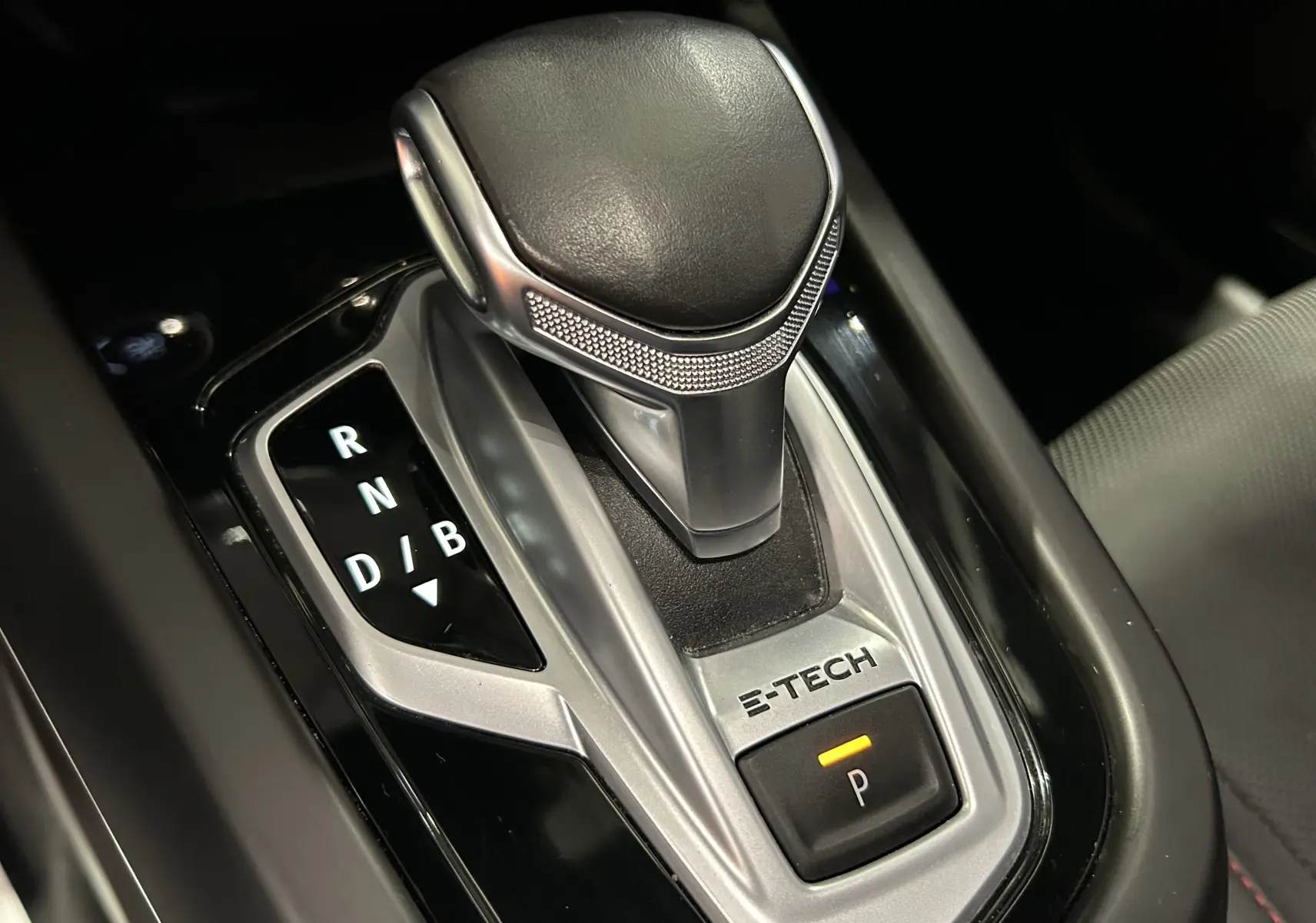 Gros plan sur la commande de boîte automatique noire avec levier et bouton E-Tech du Renault Arkana hybride.