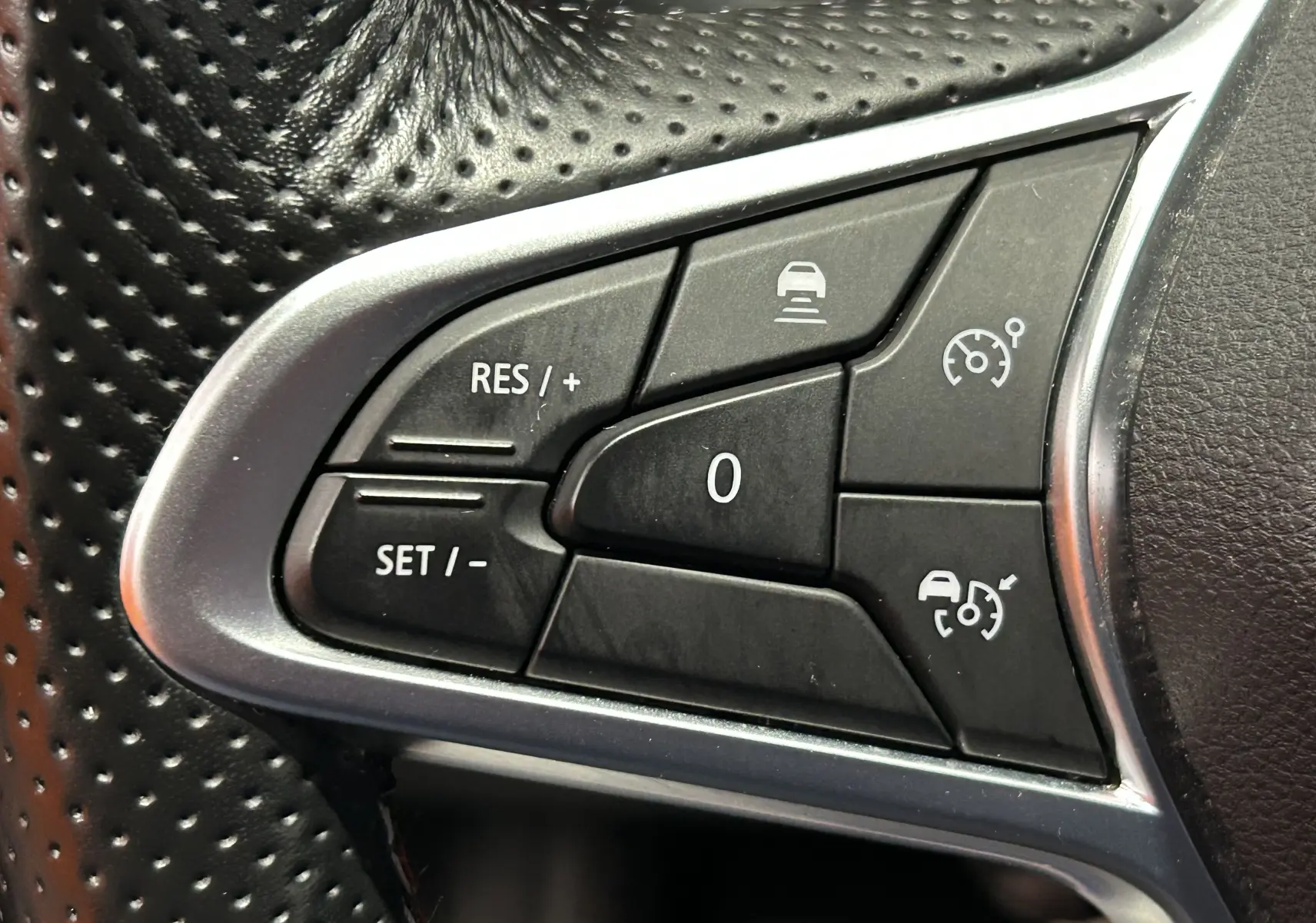 Gros plan sur les commandes de régulateur de vitesse au volant en cuir perforé noir du Renault Arkana E-Tech 2022.