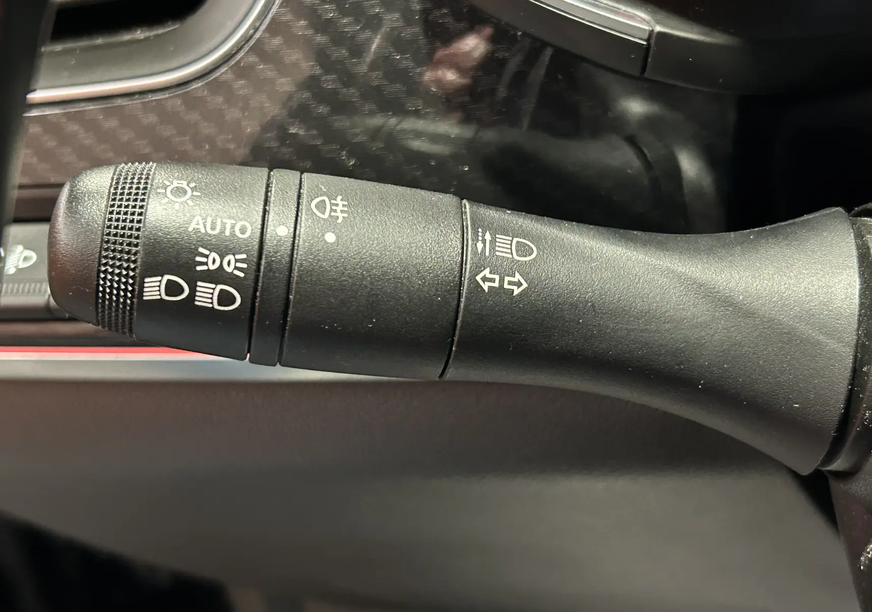 Gros plan sur la commande des feux et clignotants à gauche du volant dans l’habitacle d’un Renault Arkana noir.