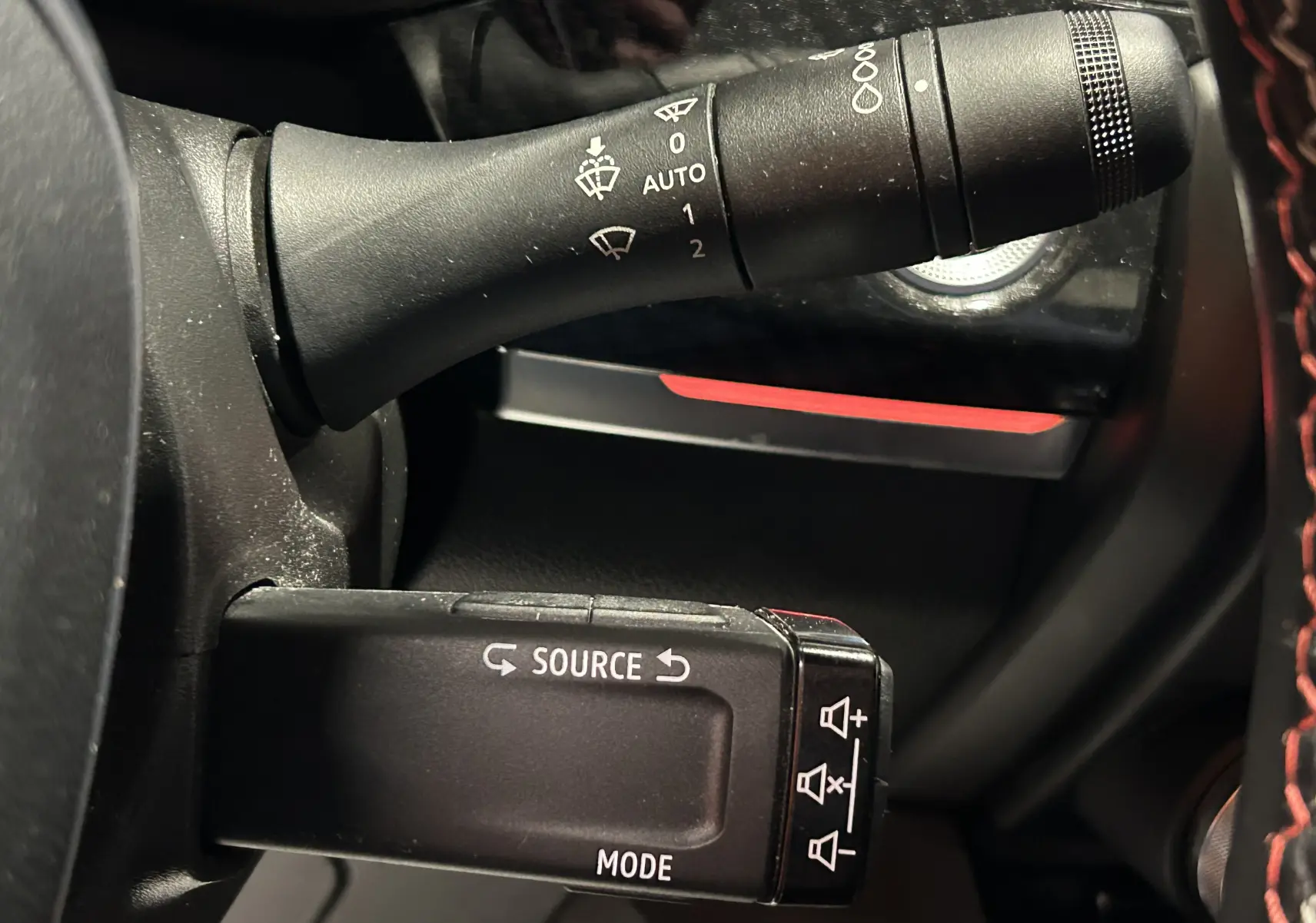 Gros plan sur les commandes au volant noir du Renault Arkana E-Tech, avec boutons source et mode visibles.