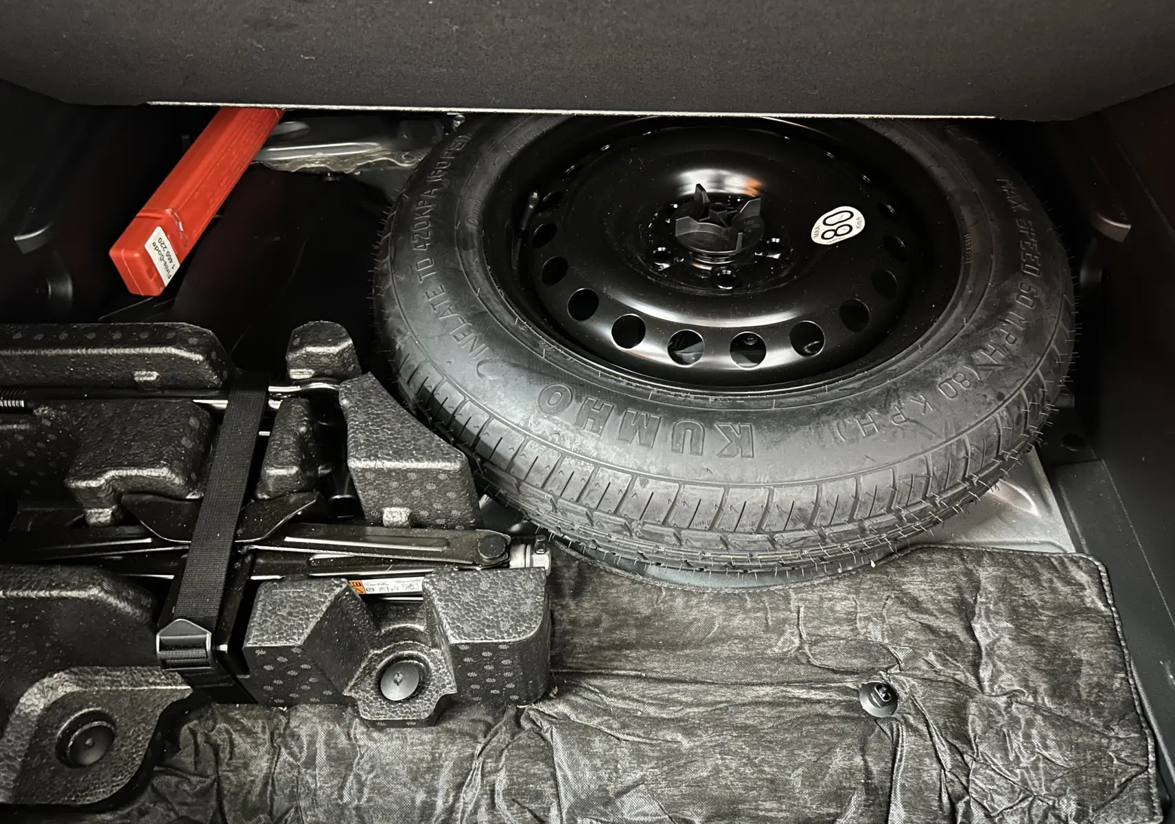 Vue du coffre montrant la roue de secours et les outils de bord du Renault Arkana noir E-Tech 145ch RS Line 2022.