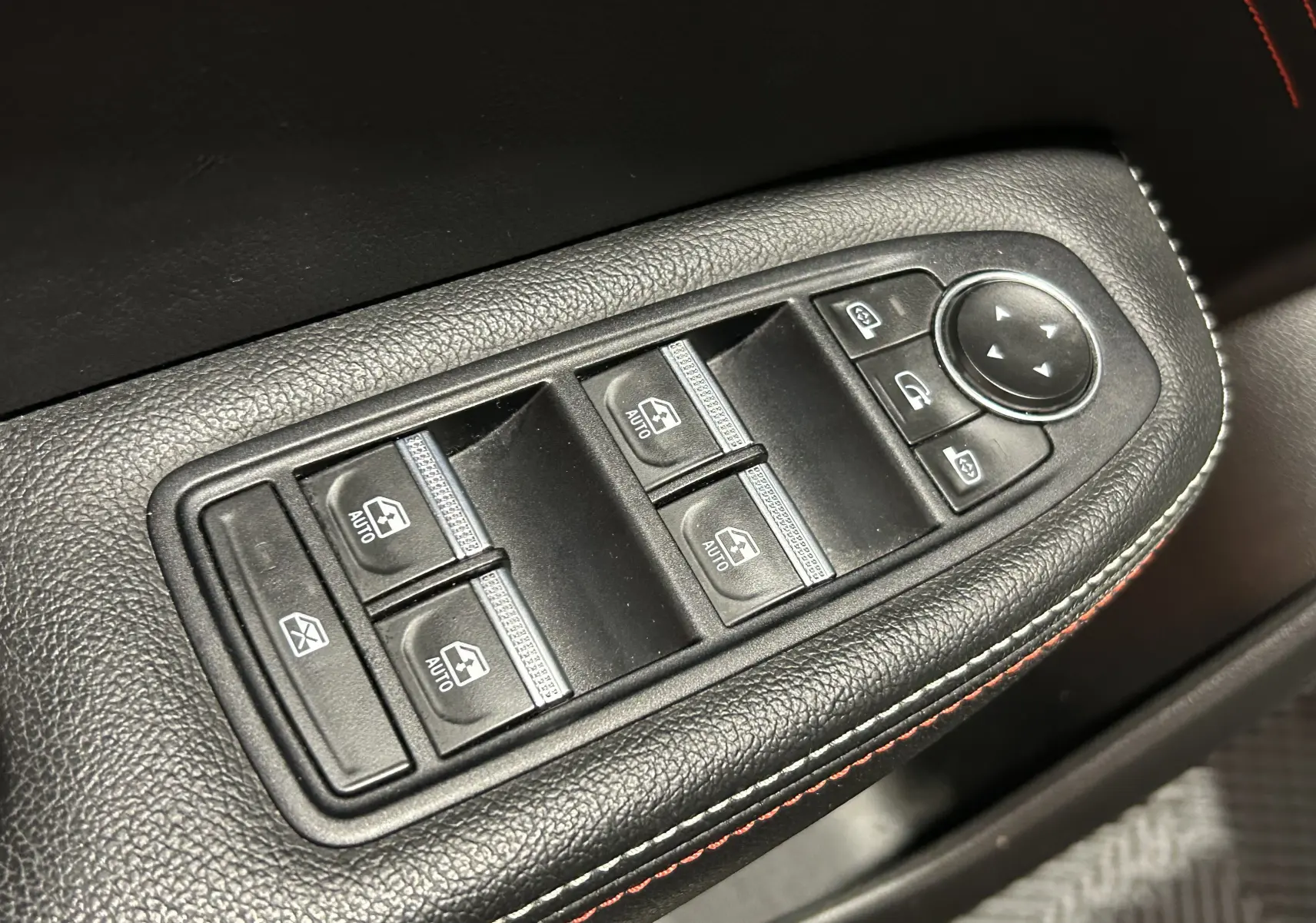 Gros plan sur les commandes de lève-vitres et rétroviseurs électriques sur la porte côté gauche du Renault Arkana noir.