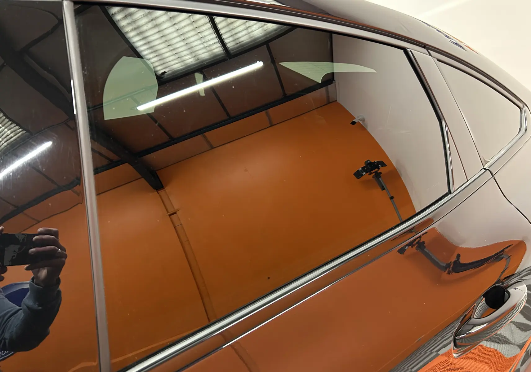 Reflet de la partie latérale droite noire d'une Renault Arkana E-Tech 145ch RS Line 2022, avec poignée de porte visible.