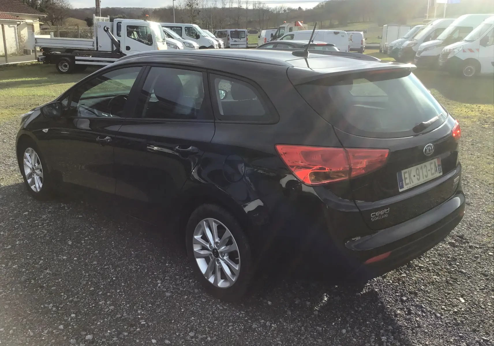 KIA CEE'D SW noire vue 3/4 arrière droit, break diesel avec jantes alliage et feux arrière allumés.