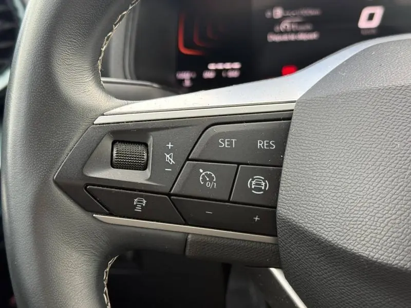 Gros plan sur les commandes au volant côté gauche du SEAT Arona 2025 gris Magnétique Métal, avec régulateur de vitesse et aides à la conduite.