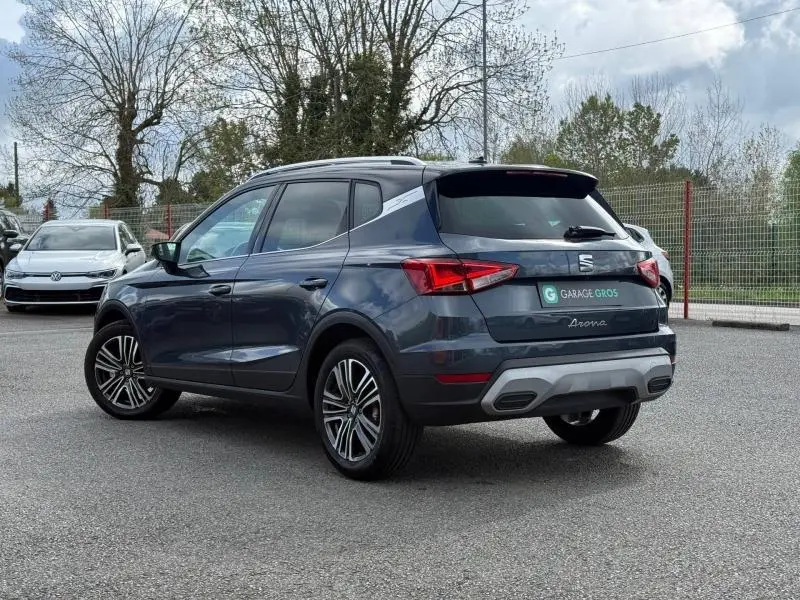 Vue 3/4 arrière droite d'un SEAT Arona 2025 gris magnétique métal avec détails Xperience et jantes alliage.