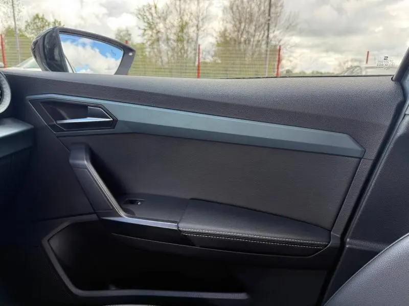 Vue intérieure côté droit de la porte du SEAT Arona 2025 avec garniture noire et insert gris mat.