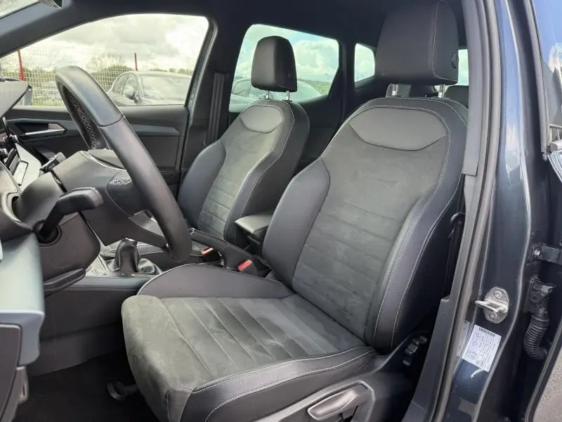 Vue intérieure côté conducteur du SEAT Arona 2025 gris Magnétique Métal, montrant les sièges en tissu et alcantara noirs.