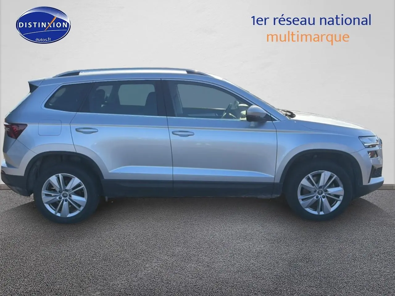 Profil droit d'un Skoda Karoq gris 2025 avec barres de toit et jantes alliage visibles.