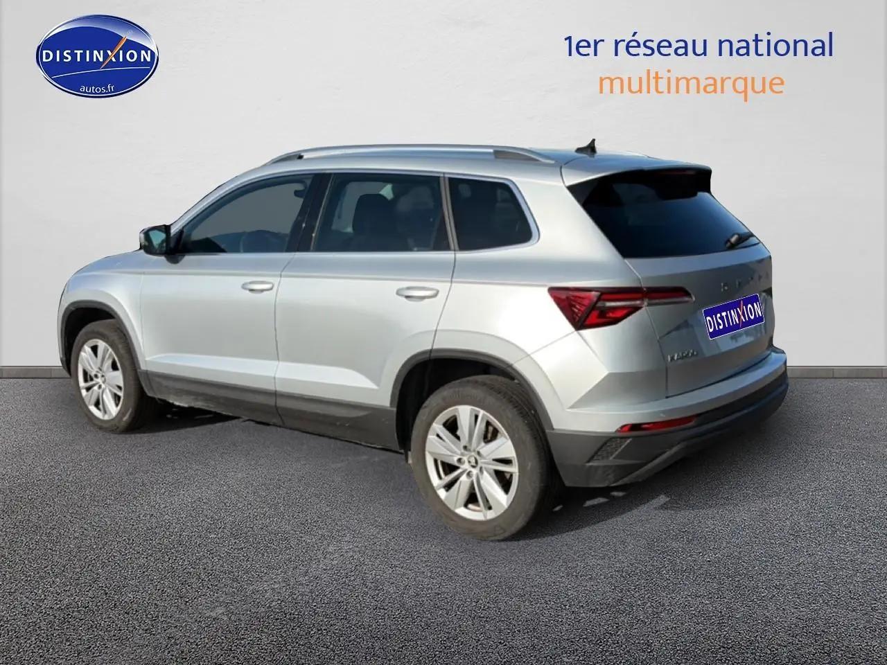 Vue 3/4 arrière droite d'un Skoda Karoq gris avec jantes alu et vitres arrière surteintées.
