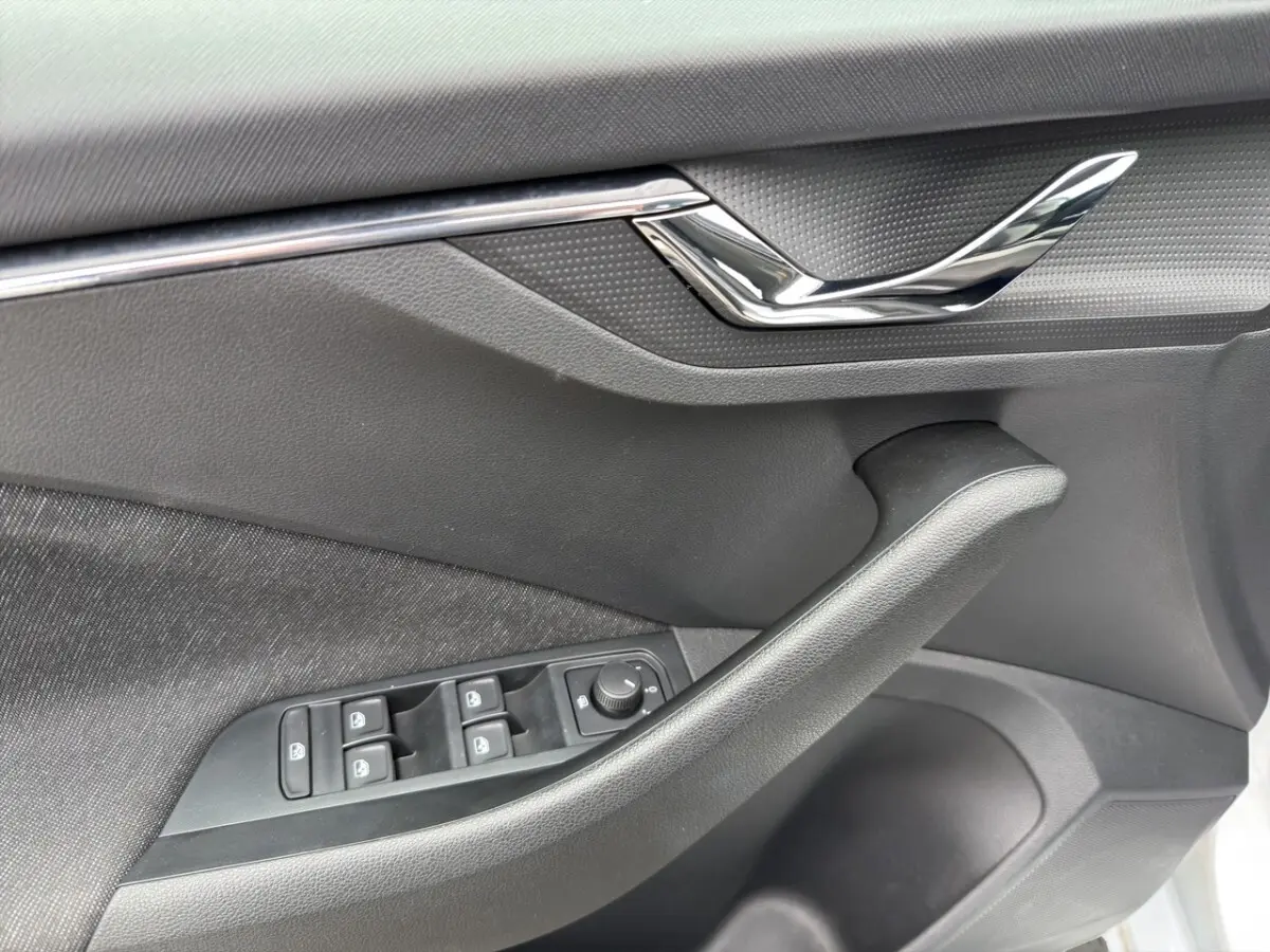 Gros plan sur la porte avant gauche du Skoda Kamiq 2023, montrant les commandes électriques des vitres et le design noir mat.