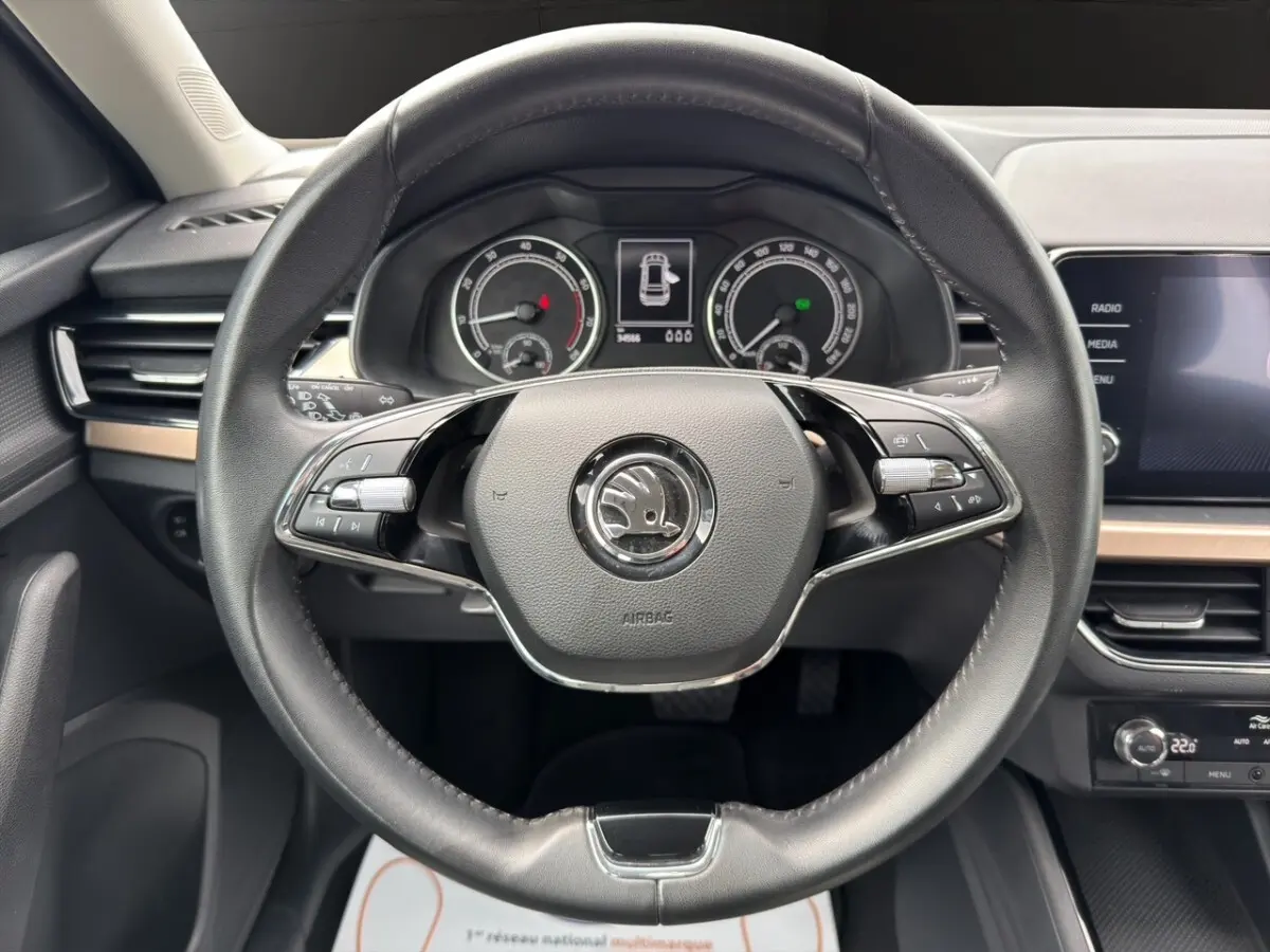 Vue rapprochée du volant cuir multifonctions et du tableau de bord digital du Skoda Kamiq 2023 gris clair.