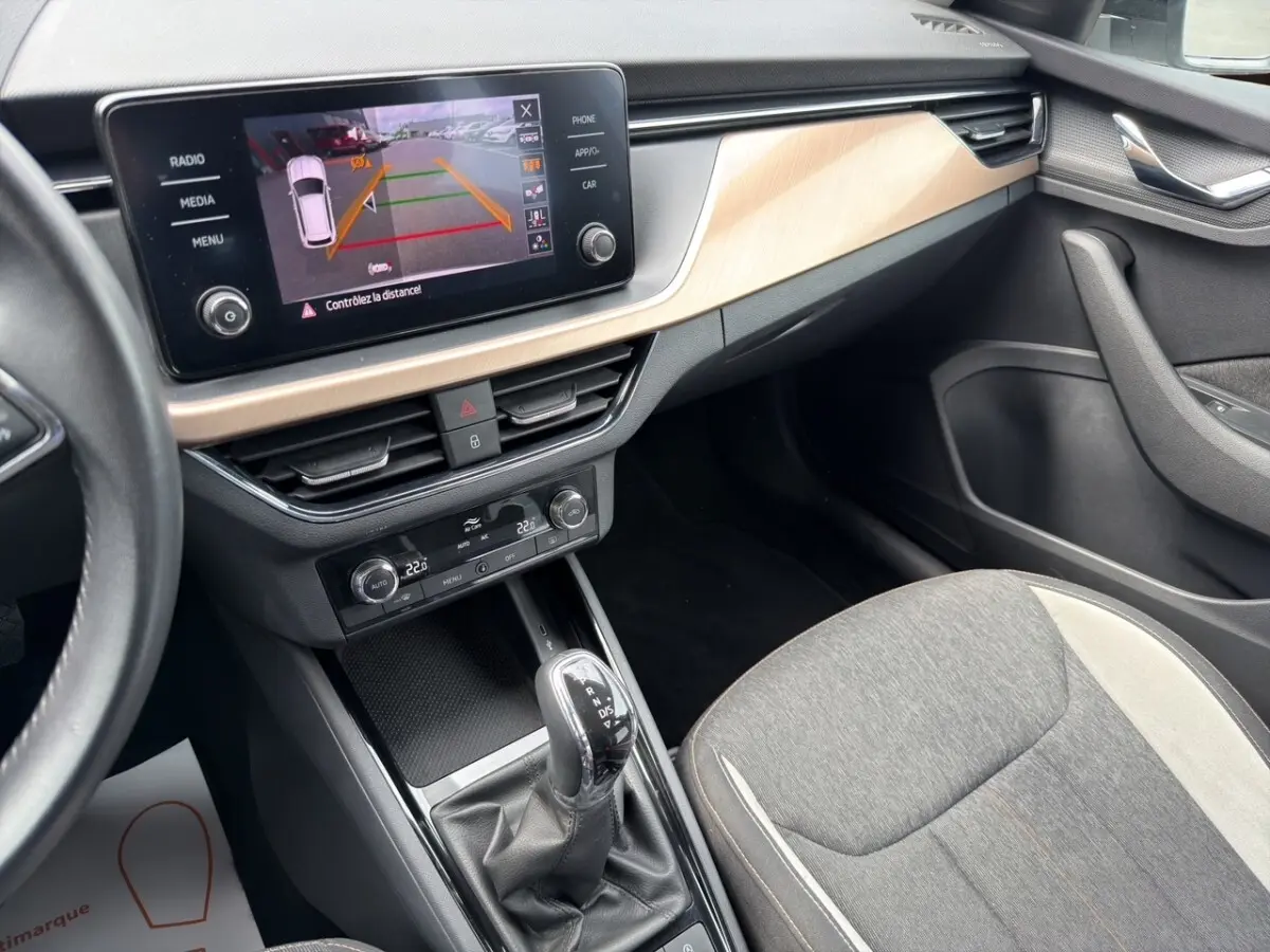 Vue intérieure côté passager du Skoda Kamiq 2023, écran tactile avec caméra de recul et sellerie tissu gris clair.