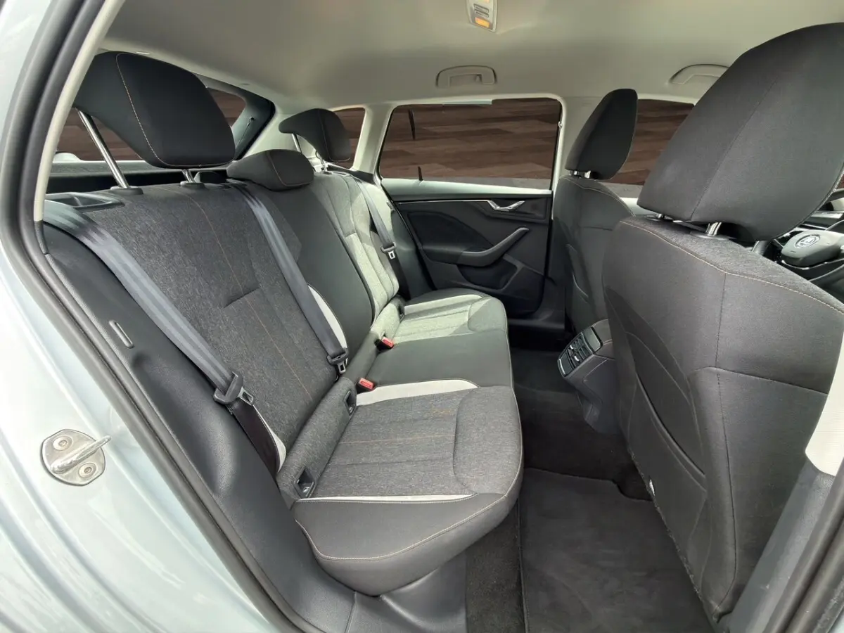 Vue intérieure côté gauche des sièges arrière gris foncé du Skoda Kamiq 2023 avec détails couture orange et accoudoir central.