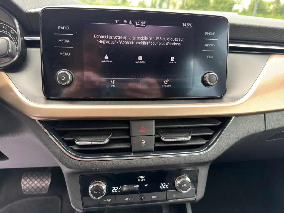 Vue rapprochée de l'écran tactile central et de la console de climatisation du Skoda Kamiq 2023, intérieur noir avec insert bois clair.