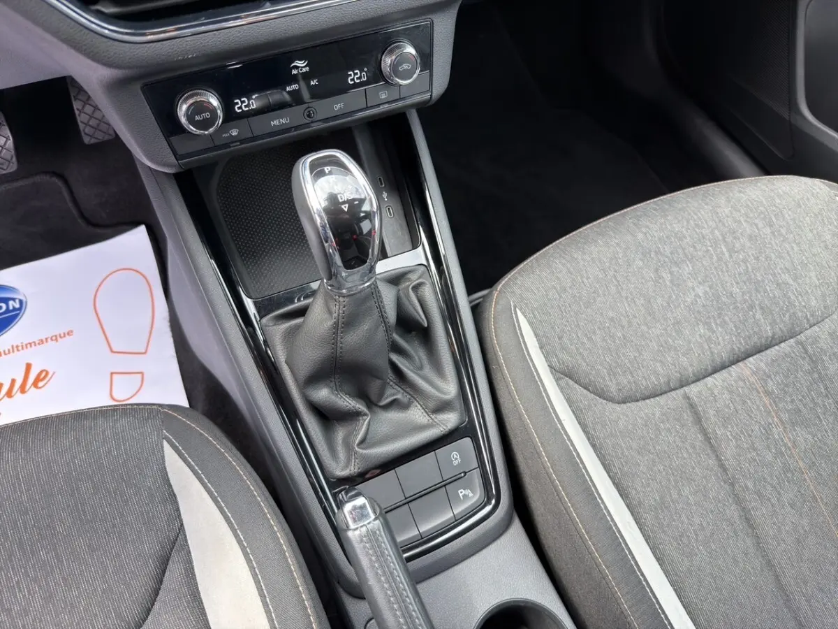 Vue rapprochée de la console centrale et levier de vitesse automatique d’un Skoda Kamiq gris clair, sièges tissu gris.