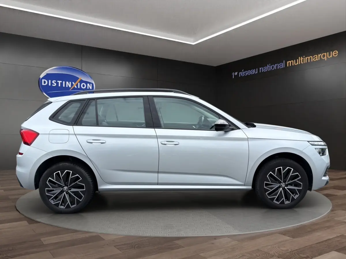 Vue latérale droite du Skoda Kamiq gris clair 2023 avec jantes bi-ton et rétroviseurs rabattables électriquement.