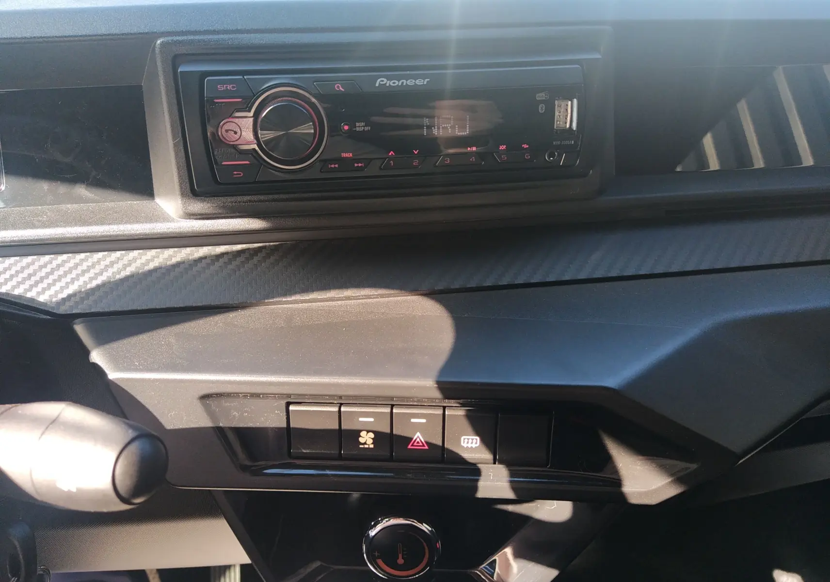 Vue rapprochée de la planche de bord noire avec autoradio Pioneer et commandes de ventilation du Ligier JS60 Revo D+ Select.