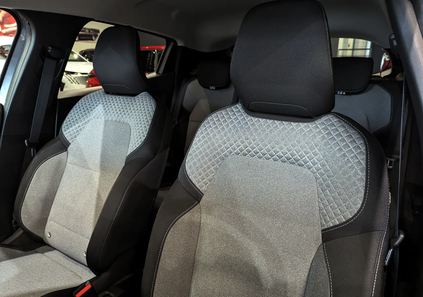 Gros plan sur les sièges avant en tissu gris clair et noir de la Renault Clio V Blue dCi 100 CH Evolution 2025.