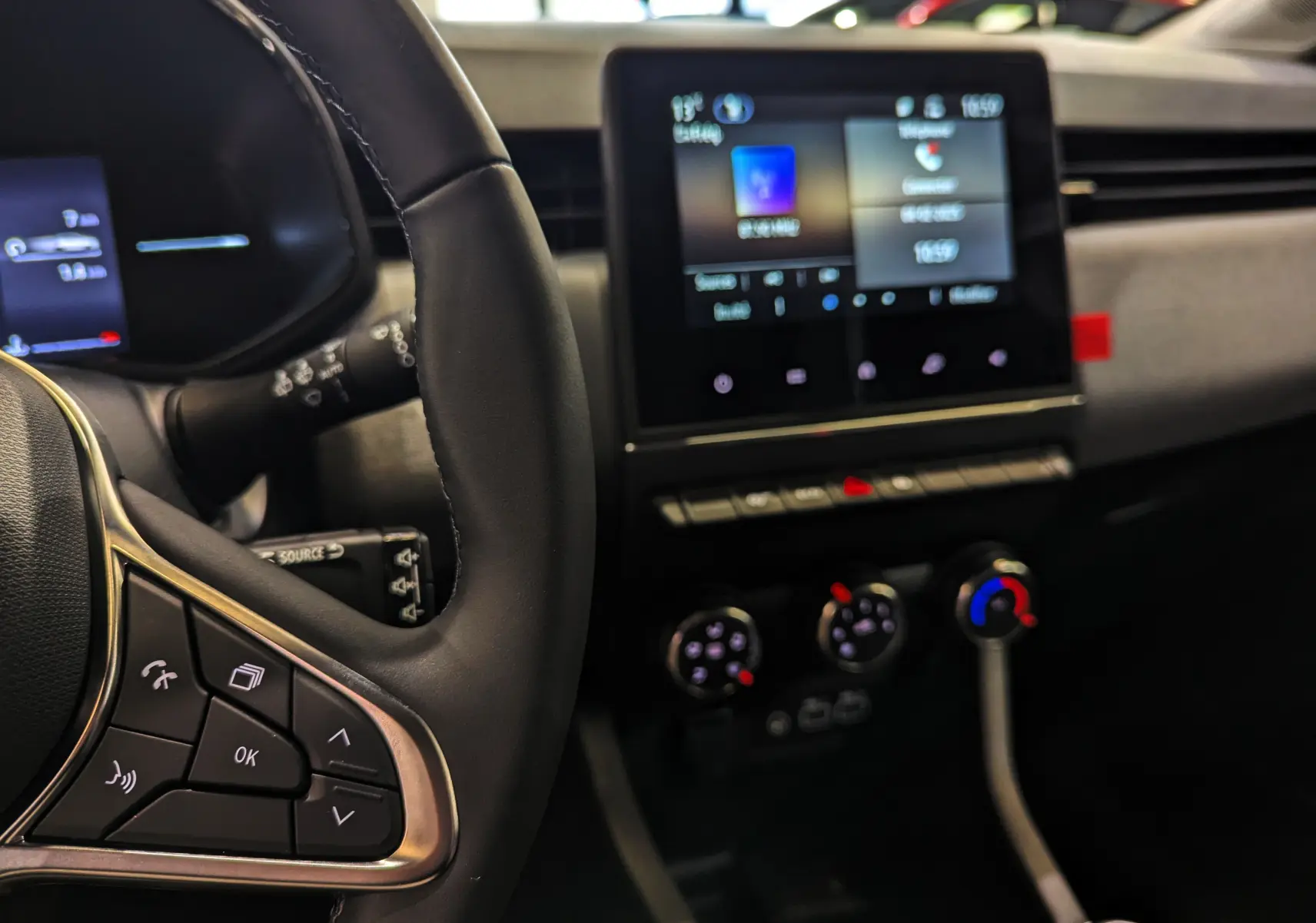 Intérieur de Renault Clio V Blue dCi 100 CH Evolution 2025, vue sur volant et écran tactile central avec commandes climatiques.