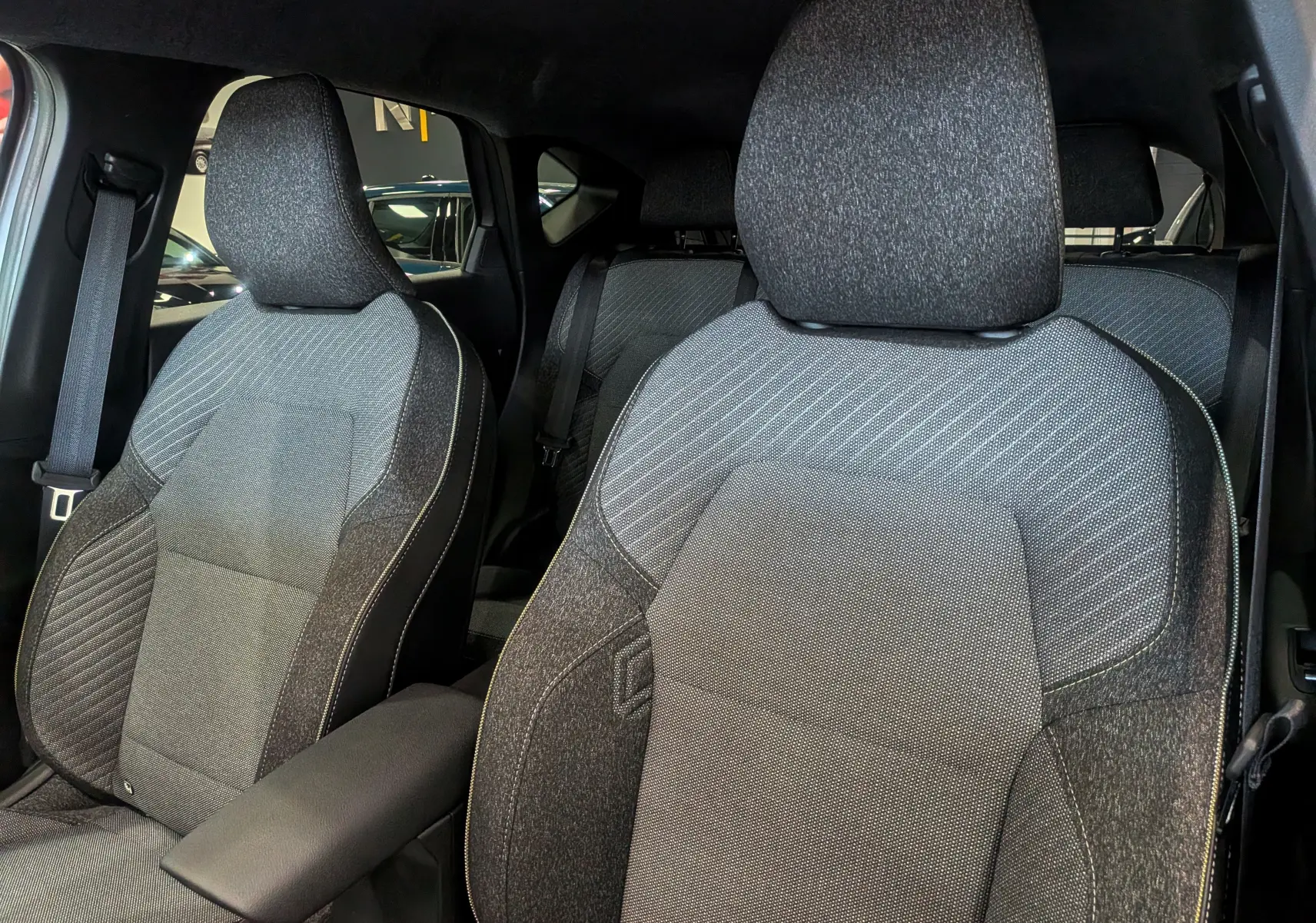 Gros plan sur les sièges avant en tissu gris foncé du Renault Captur 2025, soulignant leur design moderne et confortable.