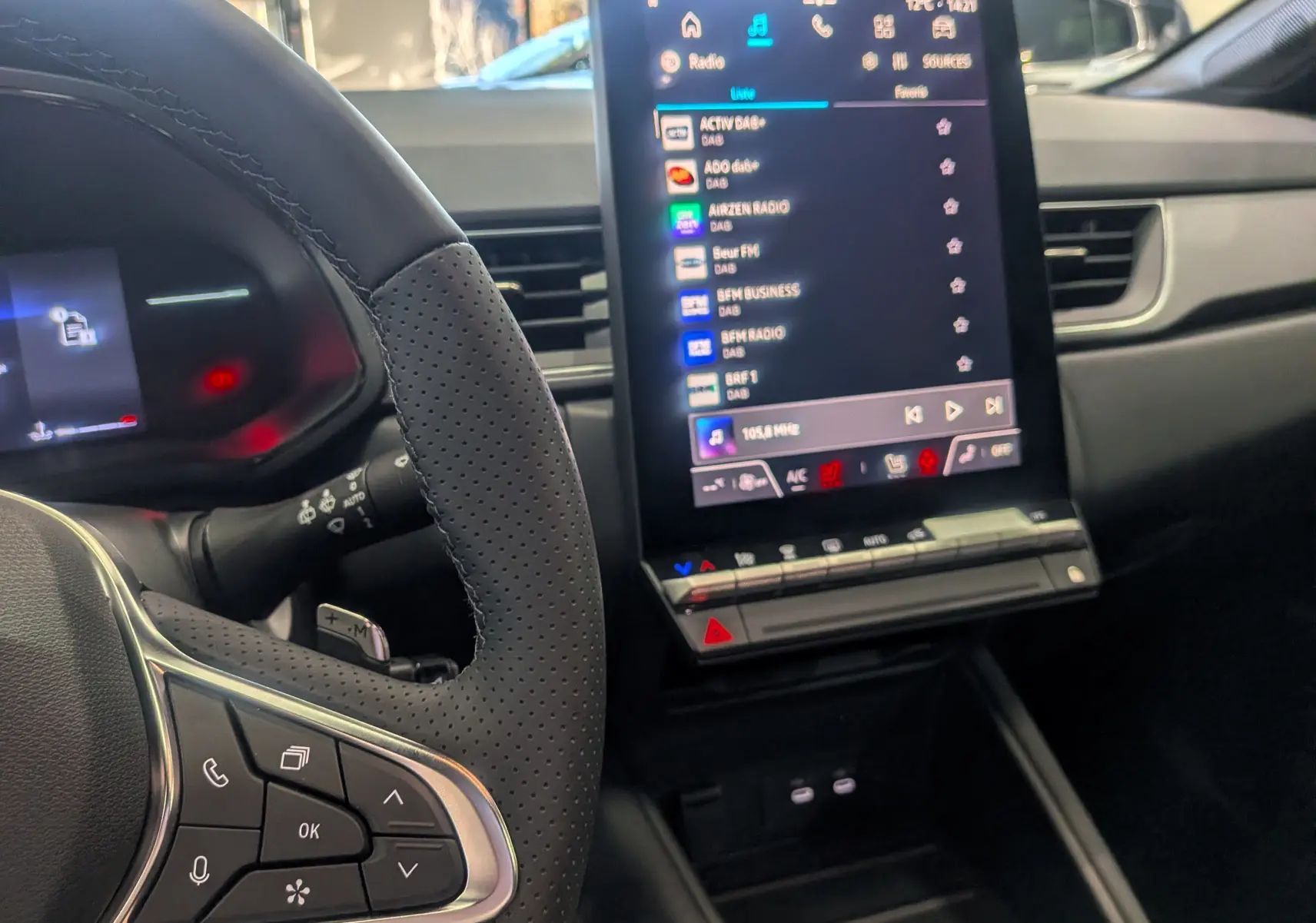 Intérieur du Renault Captur 2025, vue du volant perforé et de l'écran tactile central affichant la radio numérique.