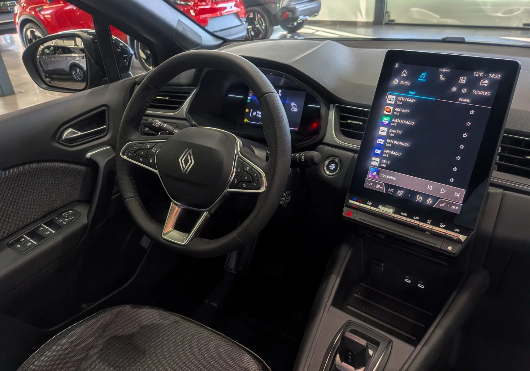 Intérieur du Renault Captur 2025 montrant le volant, la console centrale avec écran tactile vertical et sièges en tissu noir.