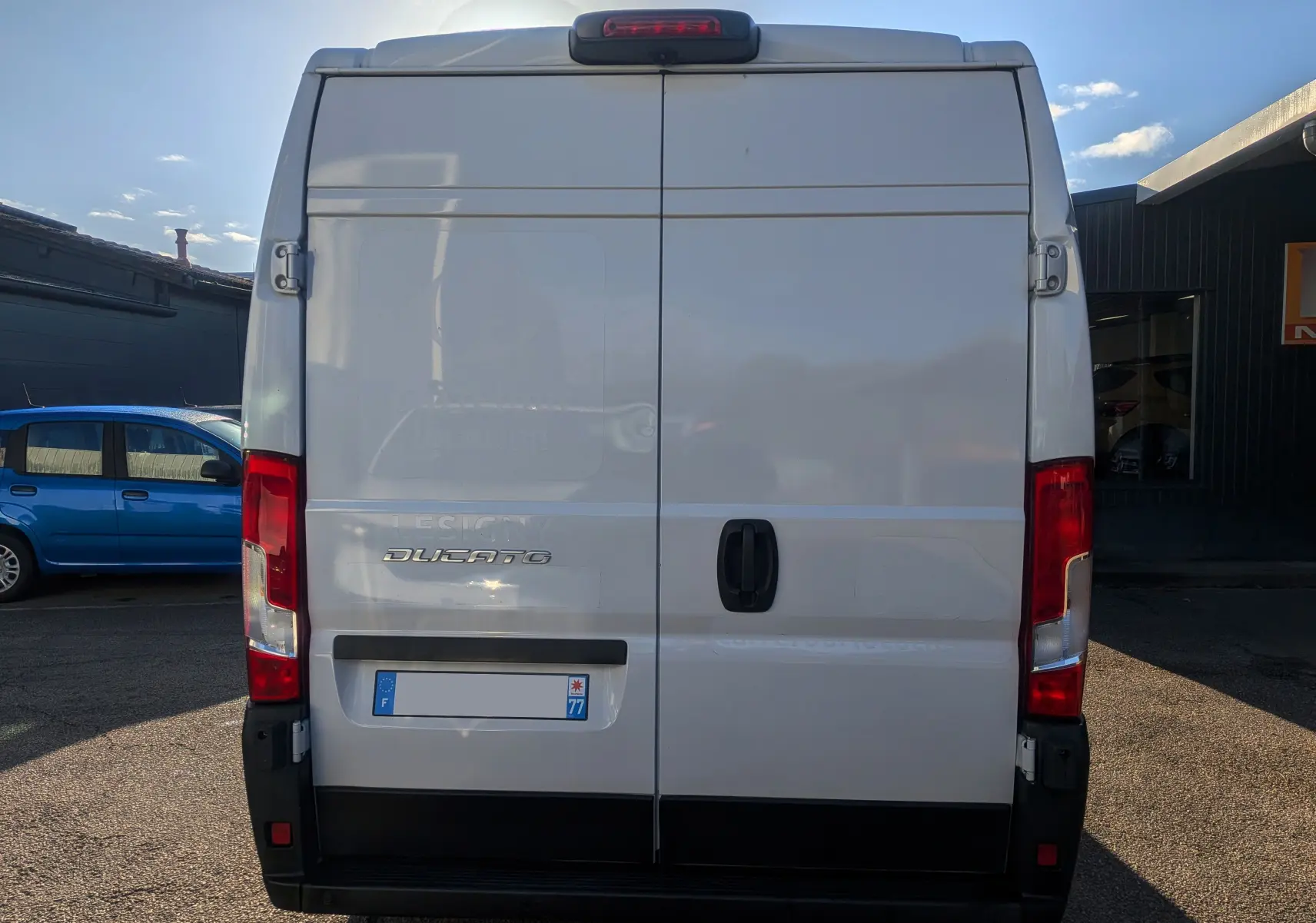 Vue arrière d'un fourgon FIAT Ducato blanc 2022 avec portes battantes et feux rouges verticaux.