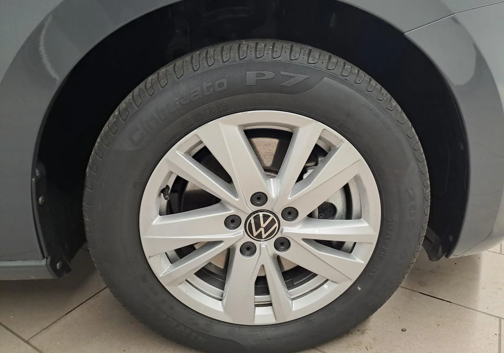 Gros plan sur la roue avant droite d'un Volkswagen Touran gris Dauphin avec jante alliage 10 branches.
