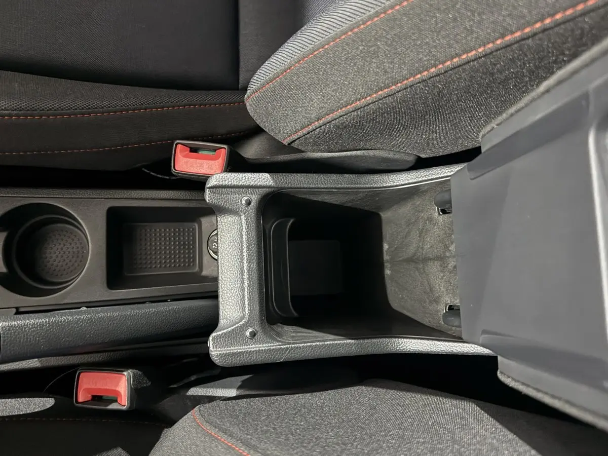 Vue plongeante sur la console centrale ouverte de la SEAT IBIZA 1.0 TSI 110 FR gris foncé, avec sièges tissu gris et coutures rouges.