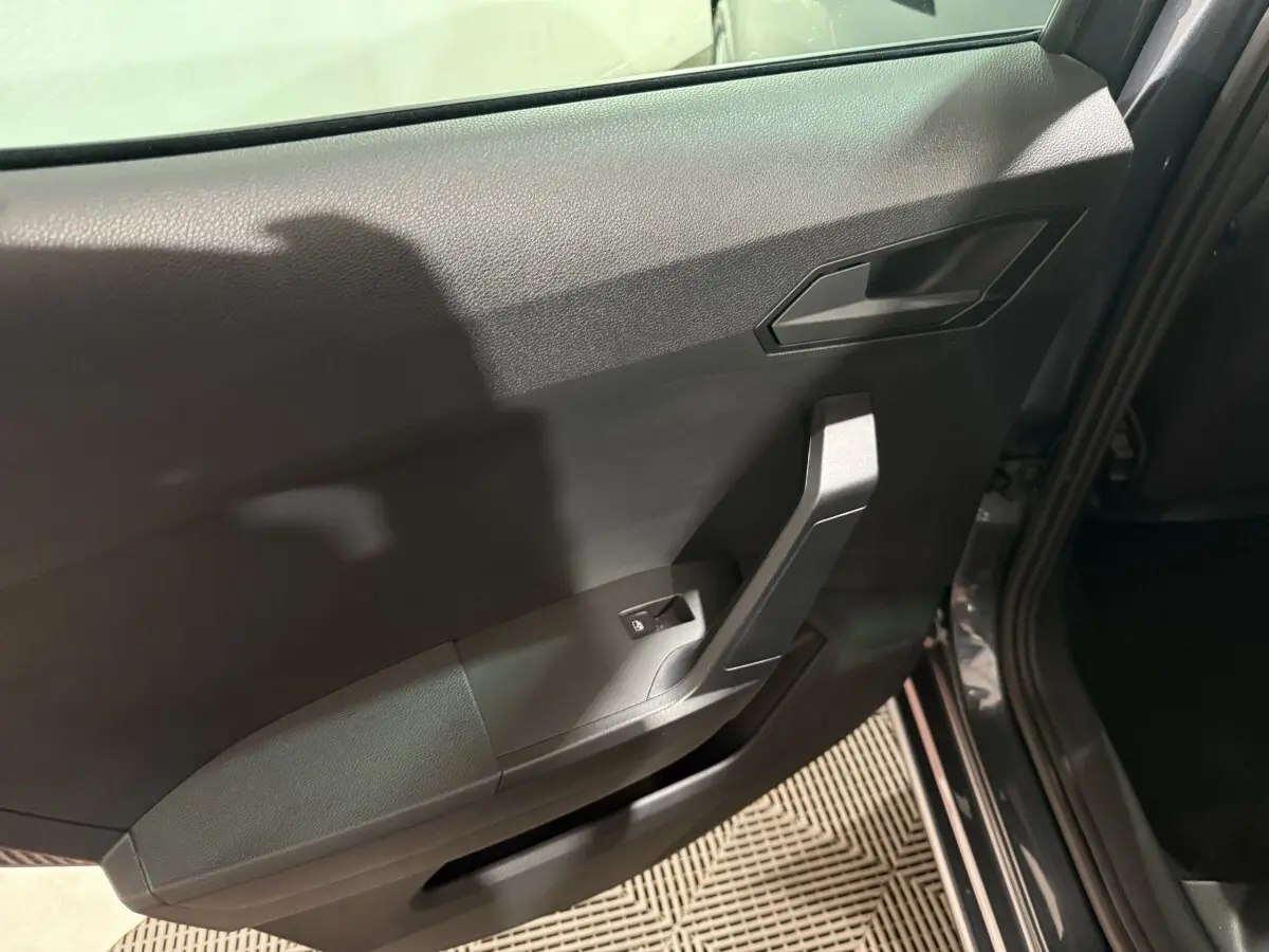 Vue intérieure côté gauche de la porte arrière grise foncée de la SEAT IBIZA 2024 avec poignée et commande de lève-vitre.