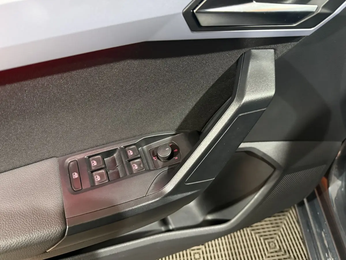 Gros plan sur la porte côté conducteur de la SEAT Ibiza gris foncé, montrant les commandes électriques des vitres et des rétroviseurs.