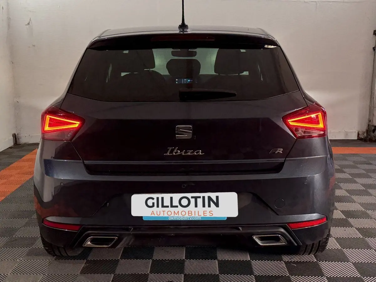 Vue arrière d'une SEAT Ibiza 1.0 TSI 110 FR gris foncé avec feux LED allumés en intérieur.