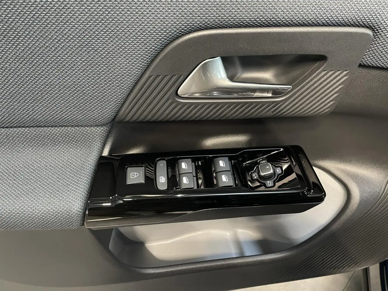 Gros plan sur la commande des vitres électriques et rétroviseurs sur la porte avant gauche d'un Citroën C5 Aircross Bleu Azul.
