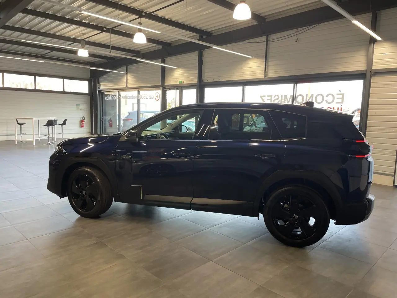 Vue de profil côté gauche du Citroën C5 Aircross bleu Azul avec jantes alliage noires dans un showroom.