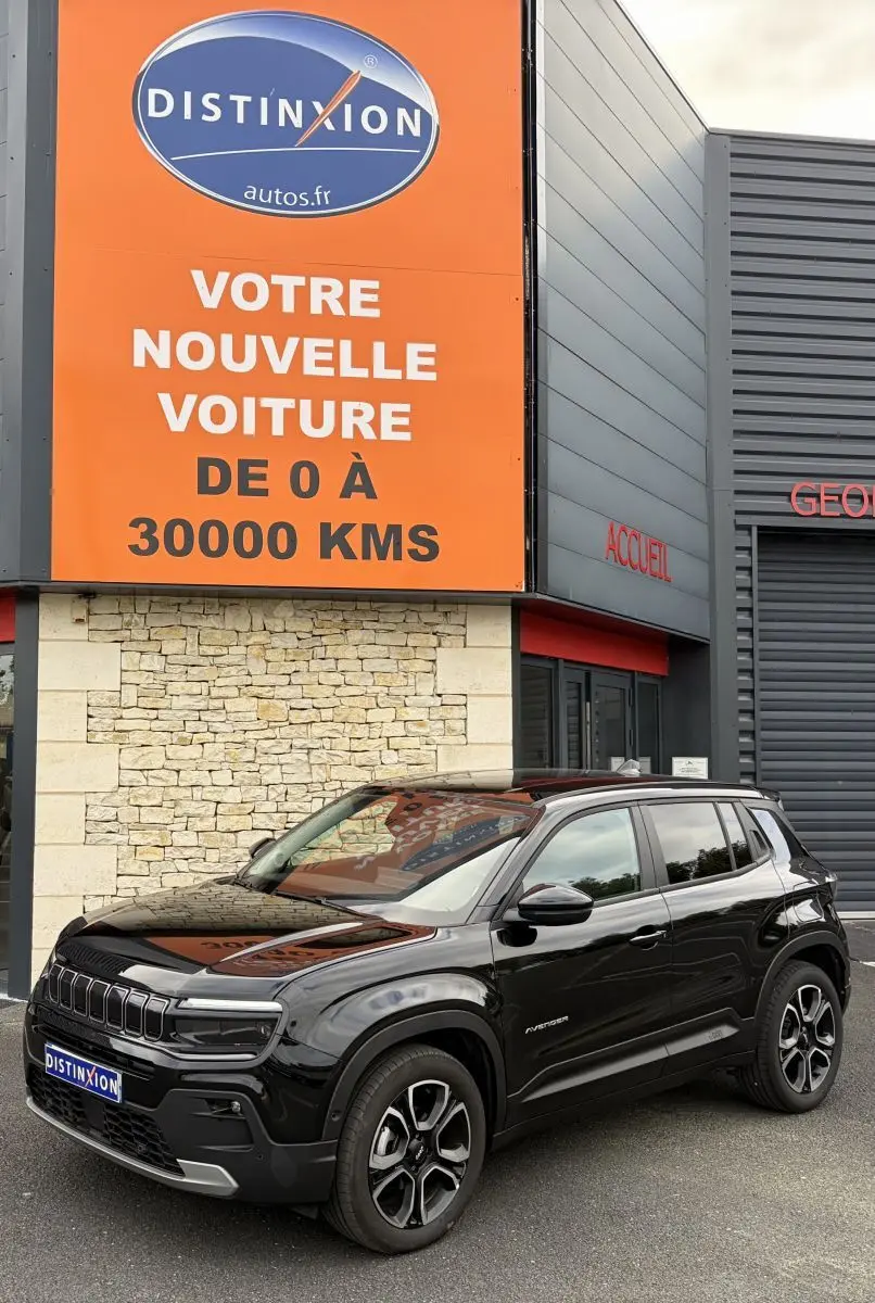 Jeep Avenger noir vue 3/4 avant droit, SUV compact avec calandre distinctive et jantes modernes, devant un bâtiment commercial.