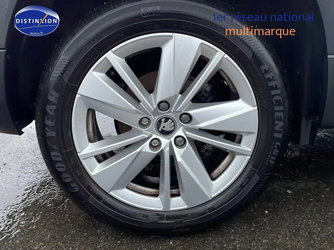 Gros plan sur la jante alu argentée avec logo Škoda, pneu Goodyear Efficient Grip visible sur un Škoda Karoq blanc glacial.