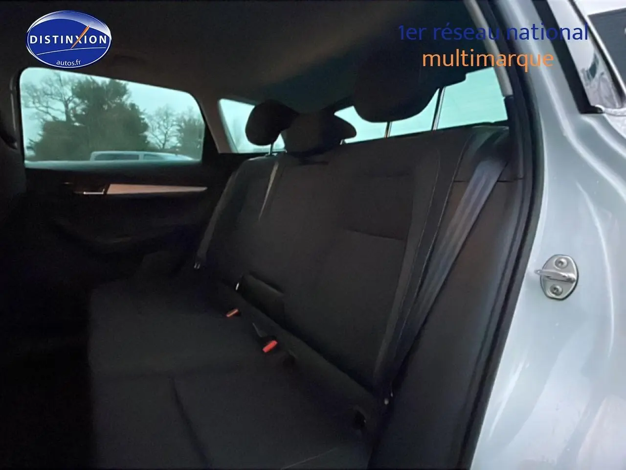 Vue intérieure côté droit sur la banquette arrière noire du Skoda Karoq blanc glacial avec porte ouverte.