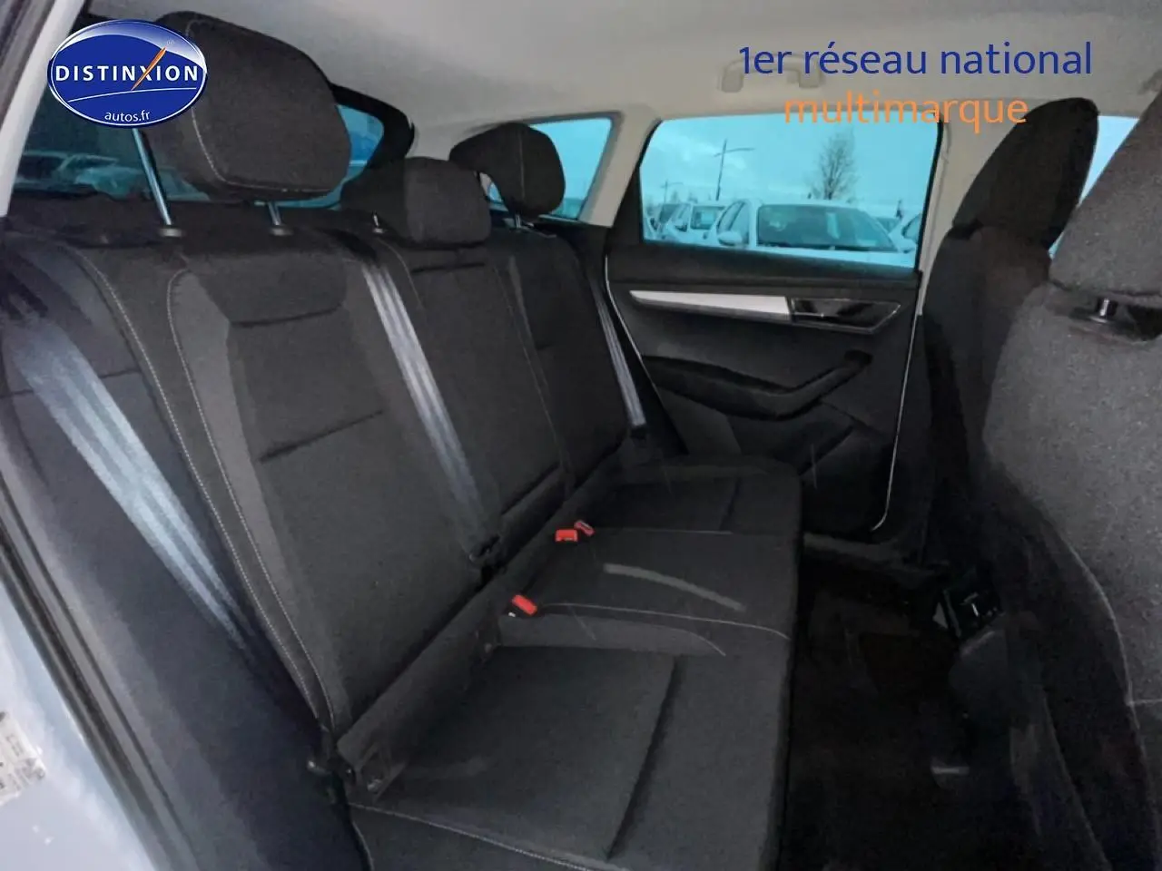 Vue intérieure arrière côté droit du Skoda Karoq blanc glacial, montrant la banquette noire et les ceintures de sécurité.