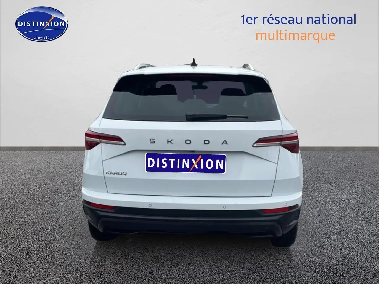 Vue arrière d'un SKODA KAROQ blanc glacial avec feux arrière LED et barres de toit visibles.