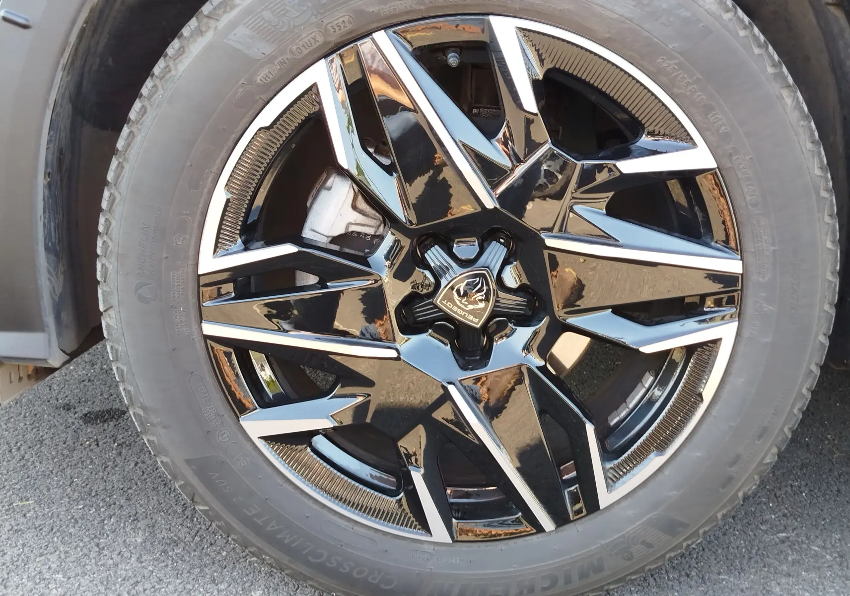 Gros plan sur la jante noire et argentée du Peugeot 3008 Bleu Obsession, mettant en valeur le logo central et le pneu Michelin.