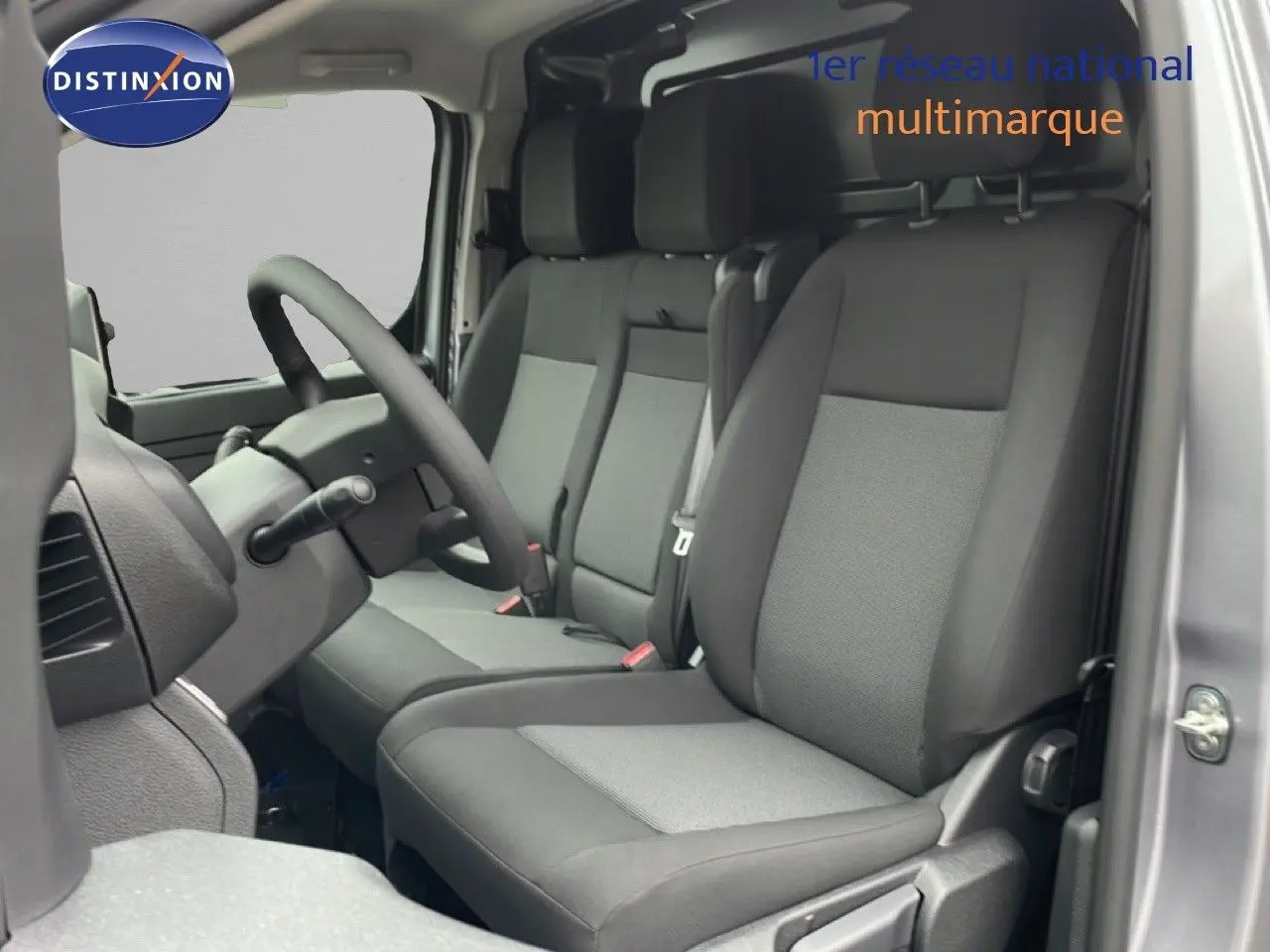 Vue intérieure côté conducteur du Citroën Jumpy 2025, montrant les sièges en tissu gris et le volant multifonction.