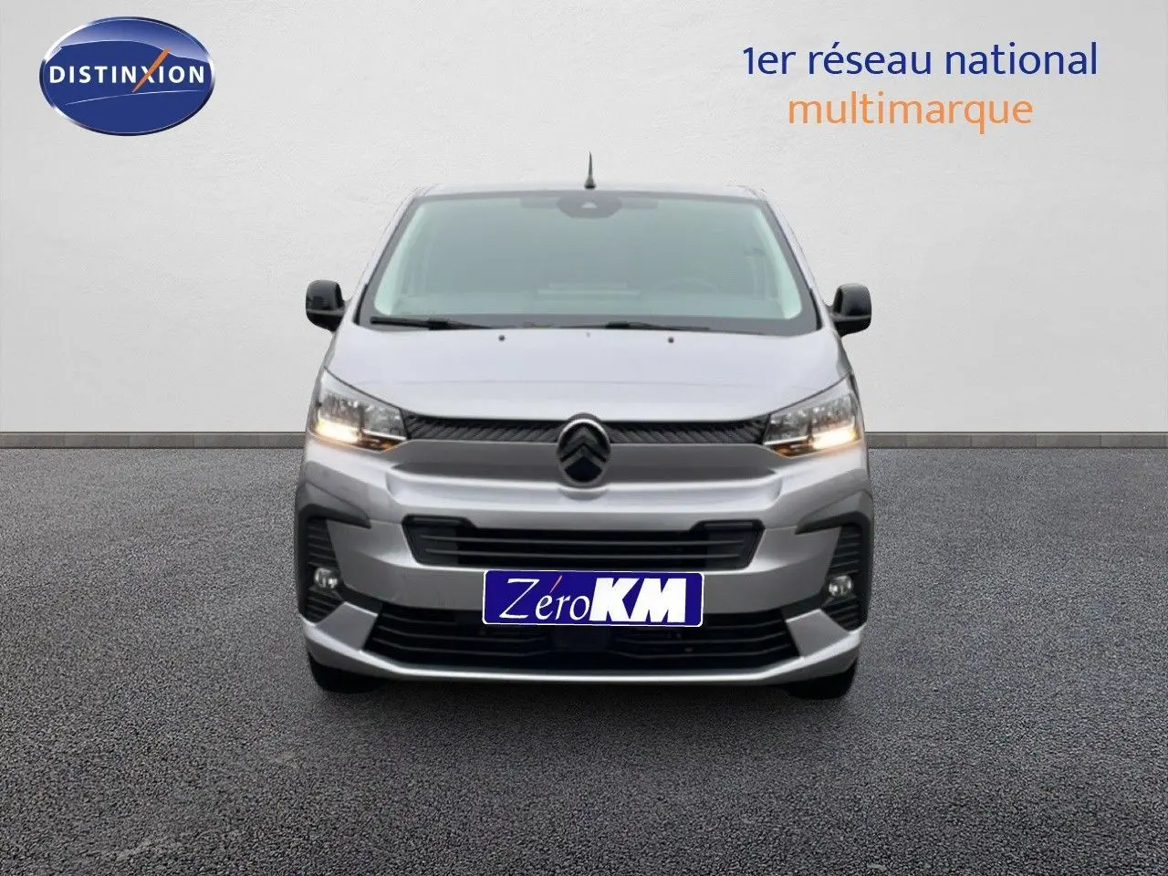 Vue de face du Citroën Jumpy Van Long L3 gris Artense métal avec calandre et phares allumés sur fond neutre.