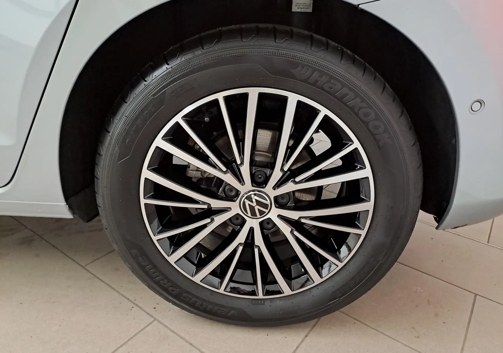 Gros plan sur la roue avant droite du Volkswagen Touran gris argent, avec jante alliage noire et argentée au design moderne.