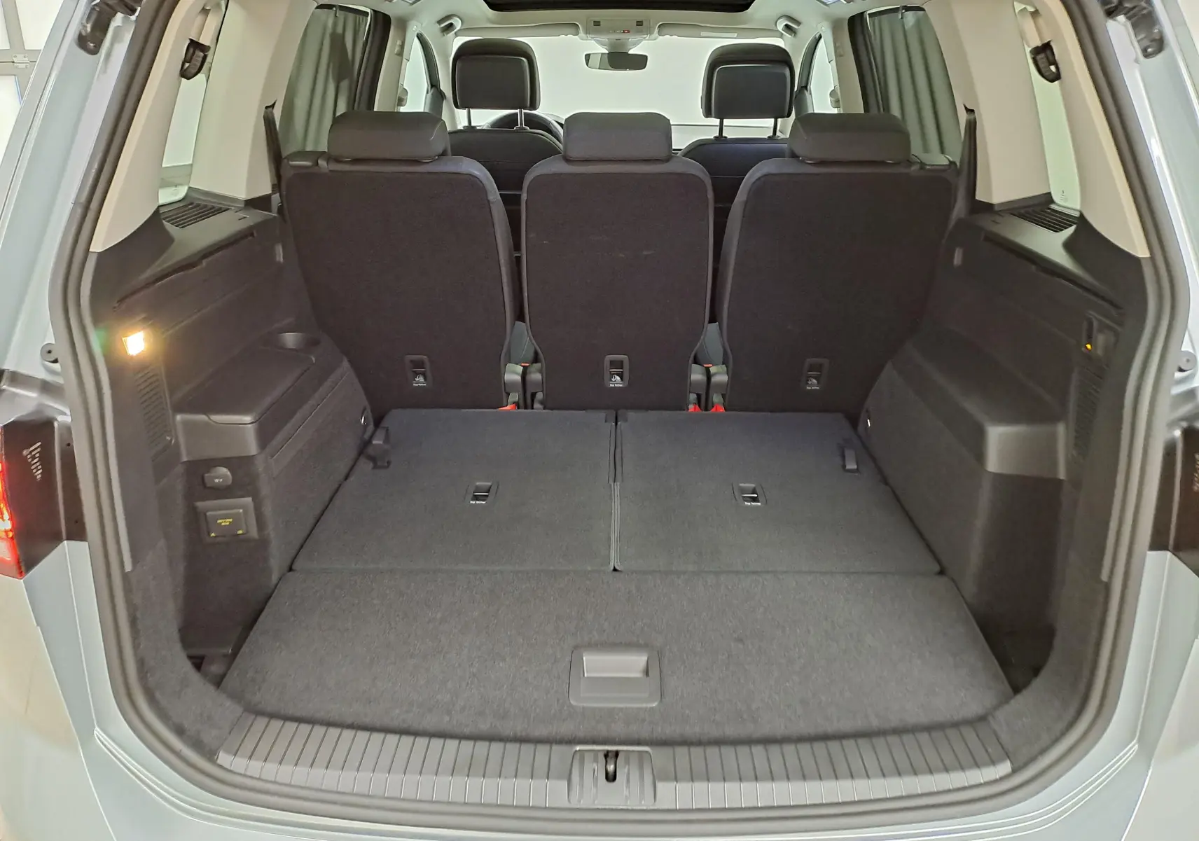 Coffre ouvert du Volkswagen Touran gris argent 2025, vue arrière montrant sièges arrière et espace de chargement modulable.