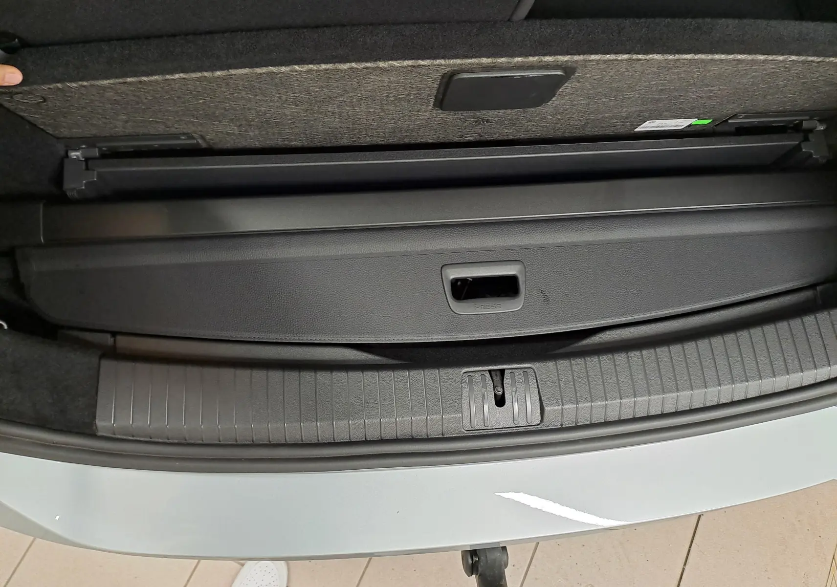 Vue plongeante sur le coffre ouvert du Volkswagen Touran gris argent, montrant la plage arrière et le seuil de chargement.